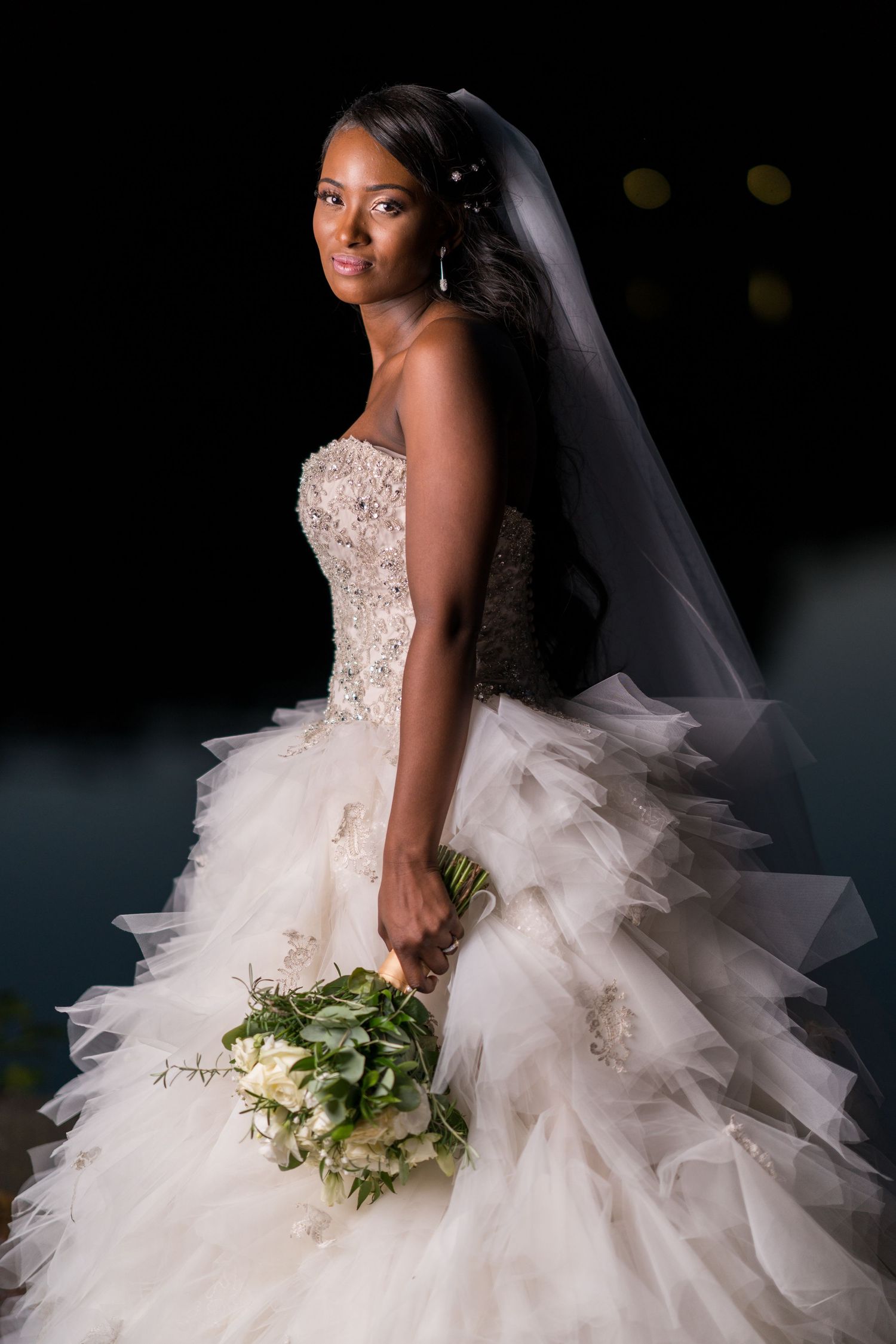 Twilight wedding. Bride's portrait as she turns to the camera. The floaty white dress and white roses bouquet make it fairytale like.