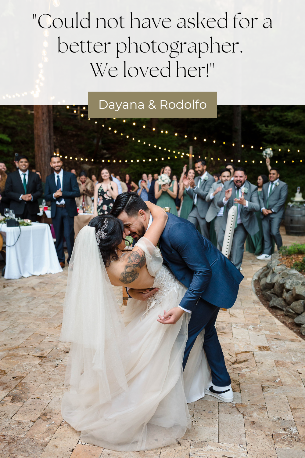 Romantic dip pose during a wedding photoshoot with string lights and wedding party in background.