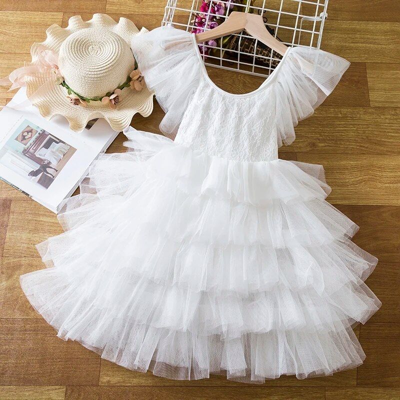 White layered tulle dress with ruffles displayed with straw hat.