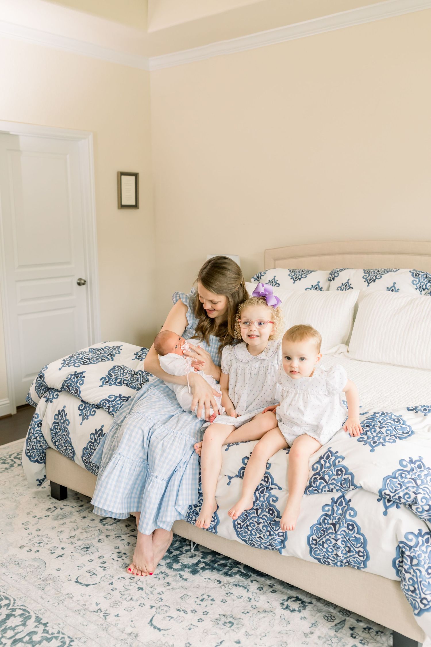 Mother sitting with children on a bed with blue damask pattern bedding.