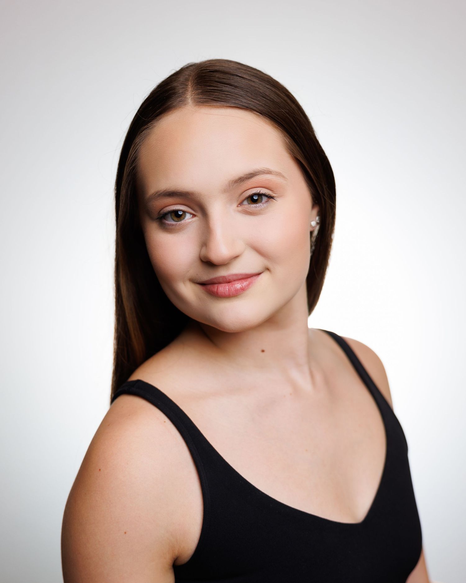 Professional headshot of dancer in black top against white background.