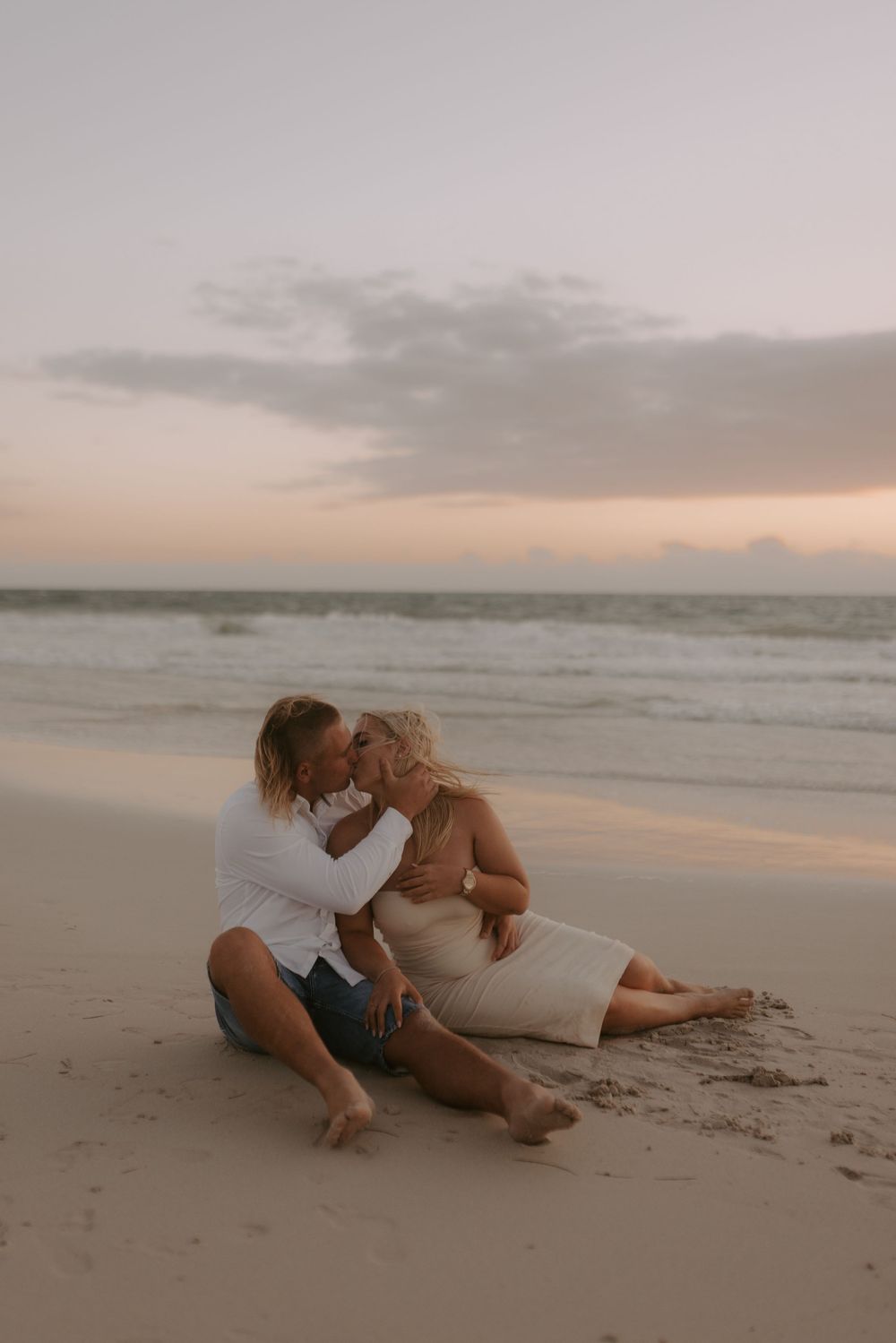Romantic couple embraces on sandy beach at sunset in series of intimate poses along shoreline.