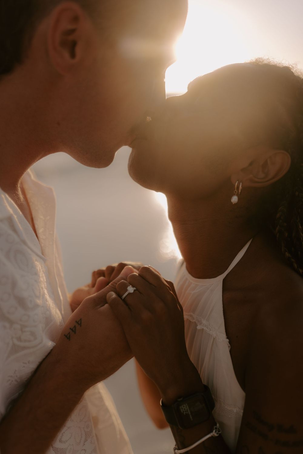 Romantic couple silhouetted against warm sunlight sharing an intimate moment on a golden evening.
