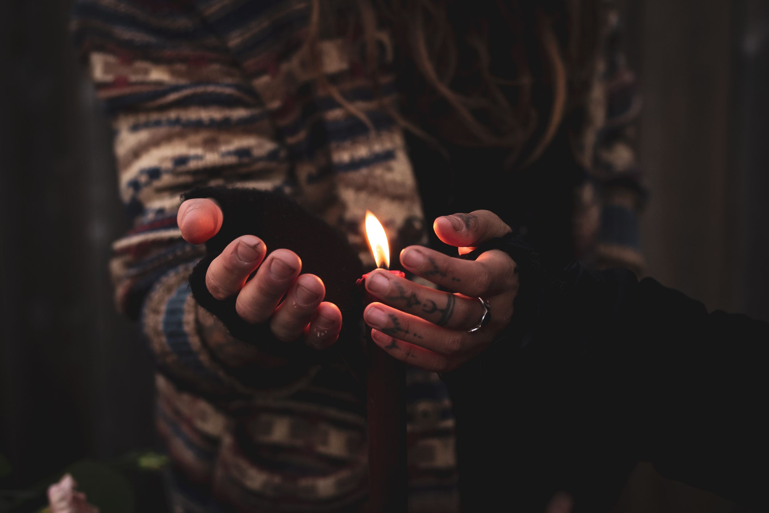 Hands holding a lit match in the dark with painted nails creating a moody atmosphere.