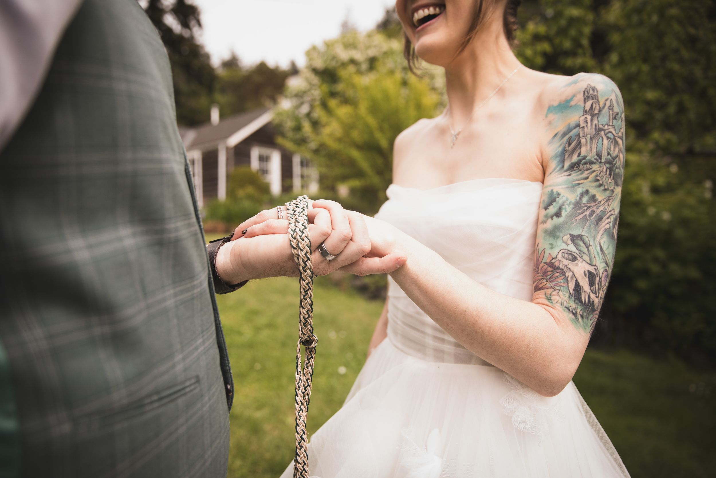 A close-up of wedding details showing a white dress and tattooed arm.