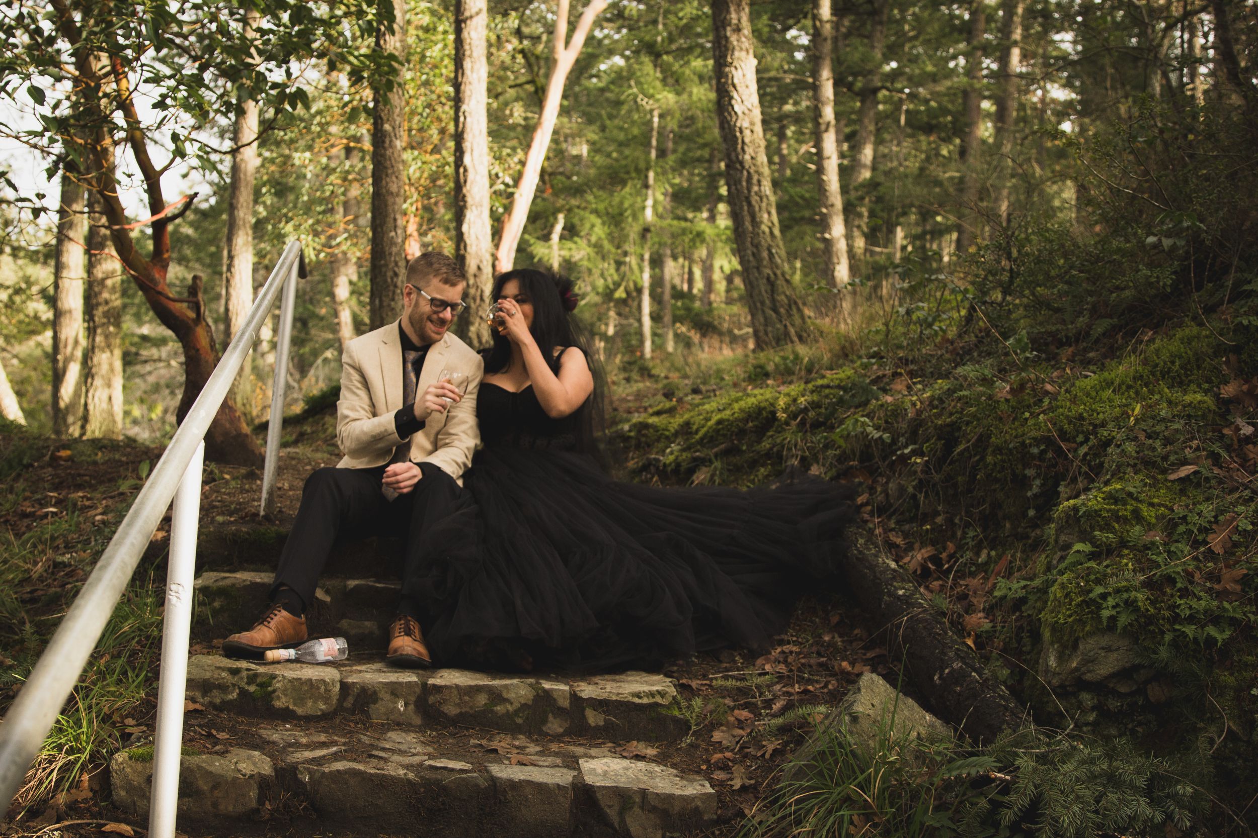 Couple in formal attire sharing intimate moment on forest steps.