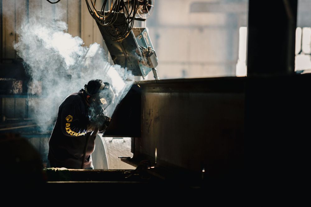 Industrial welding scene with sparks flying in dark workshop environment.
