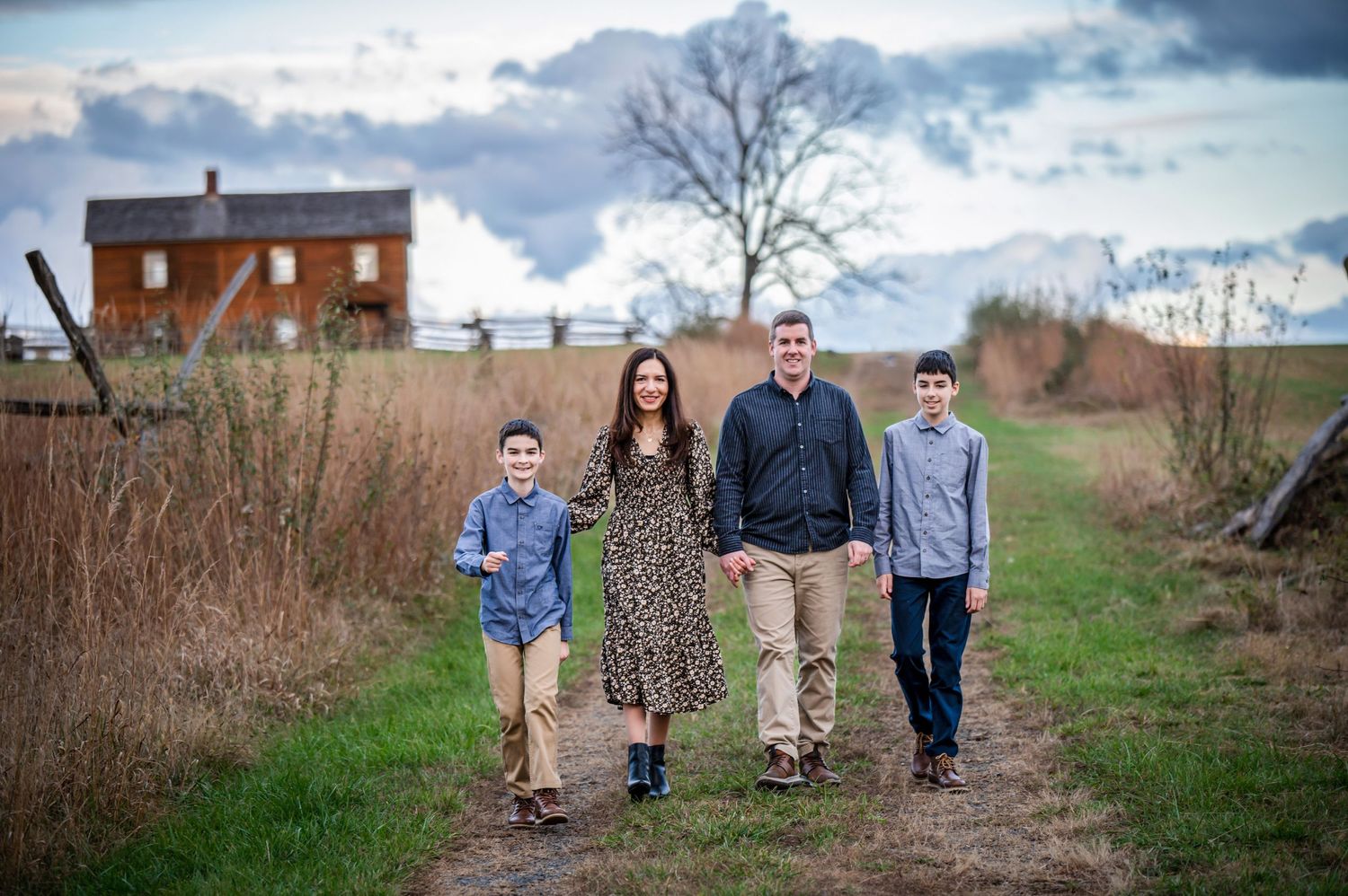 Group walking along a countryside path with an old brick house in the background.