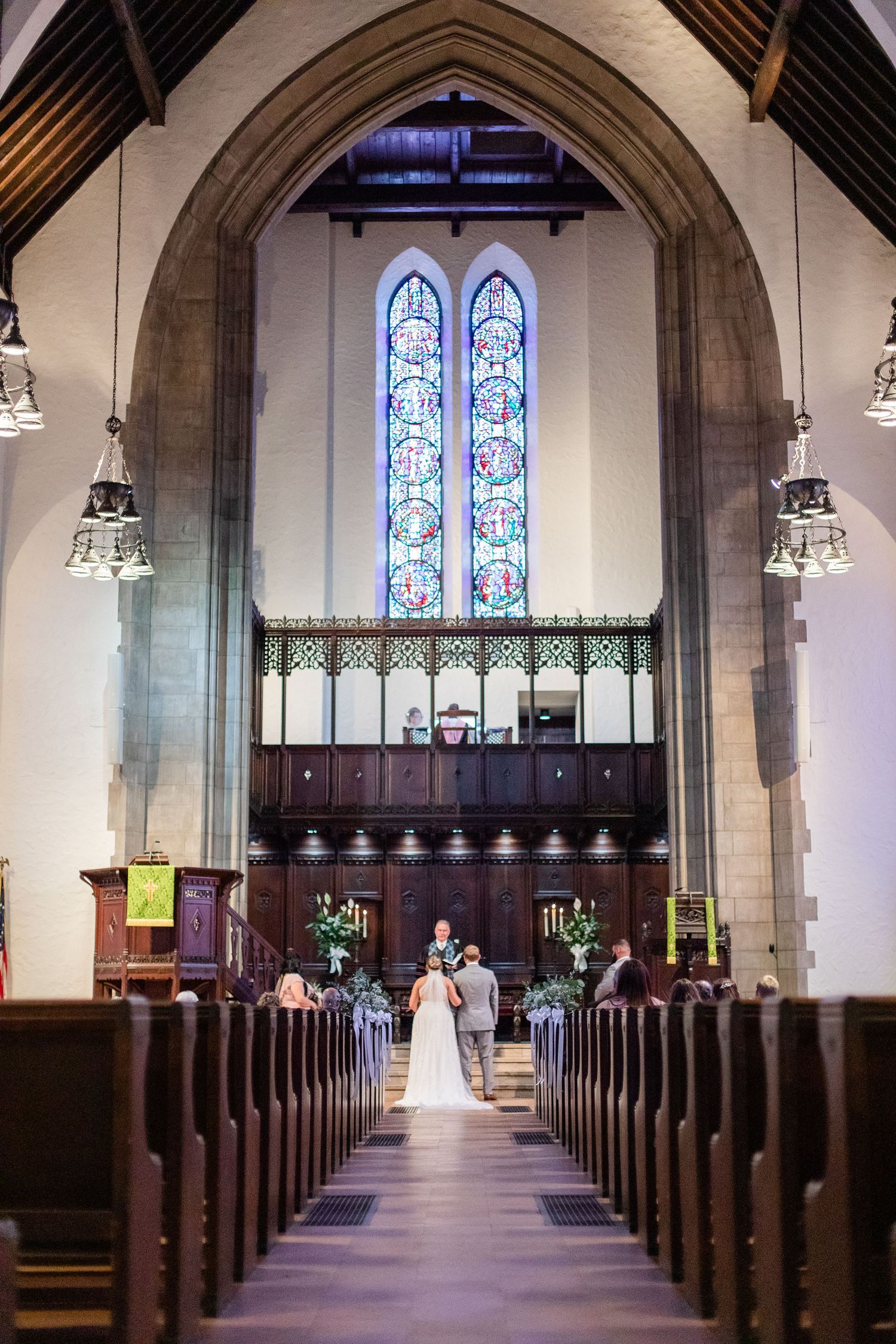Interior view of a traditional church sanctuary with wooden pews and stained glass windows.