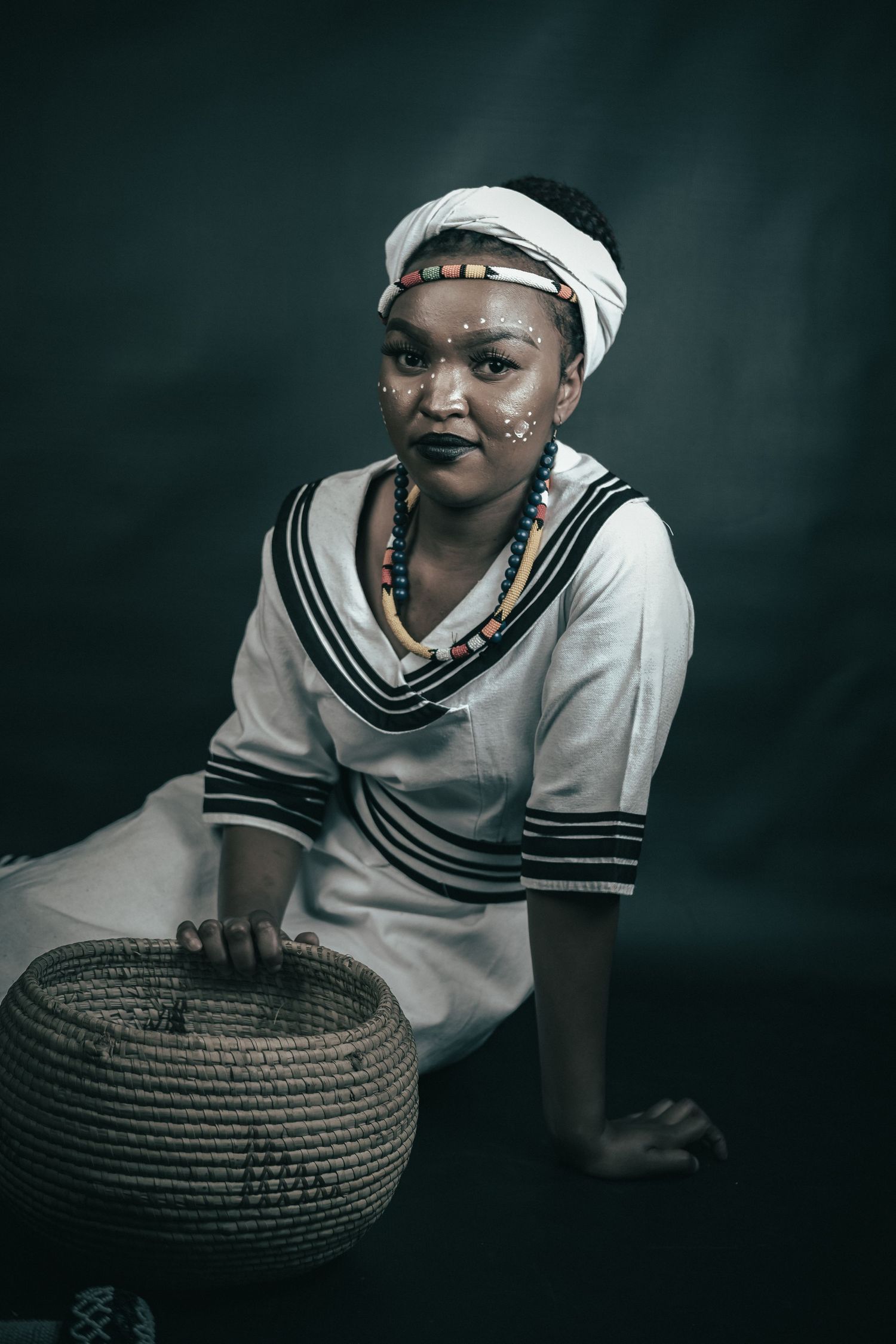 Studio shoot, of a lady celebrating her Xhosa heritage, dramatic and story telling images. With a basket as reference to offer gifts.
