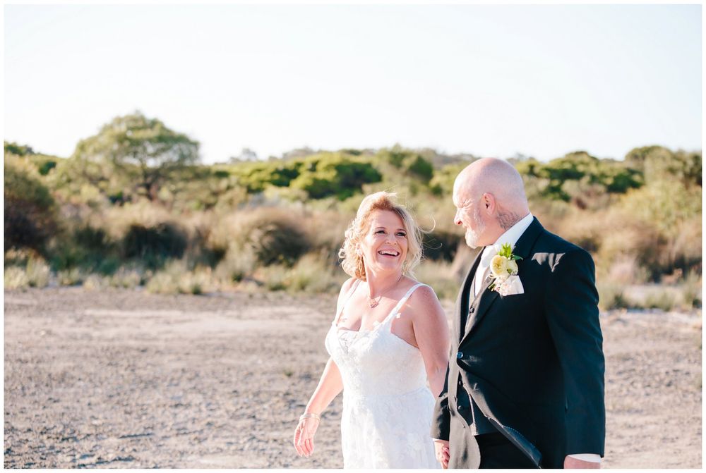 A couple sharing a joyful moment together during their outdoor wedding photoshoot.