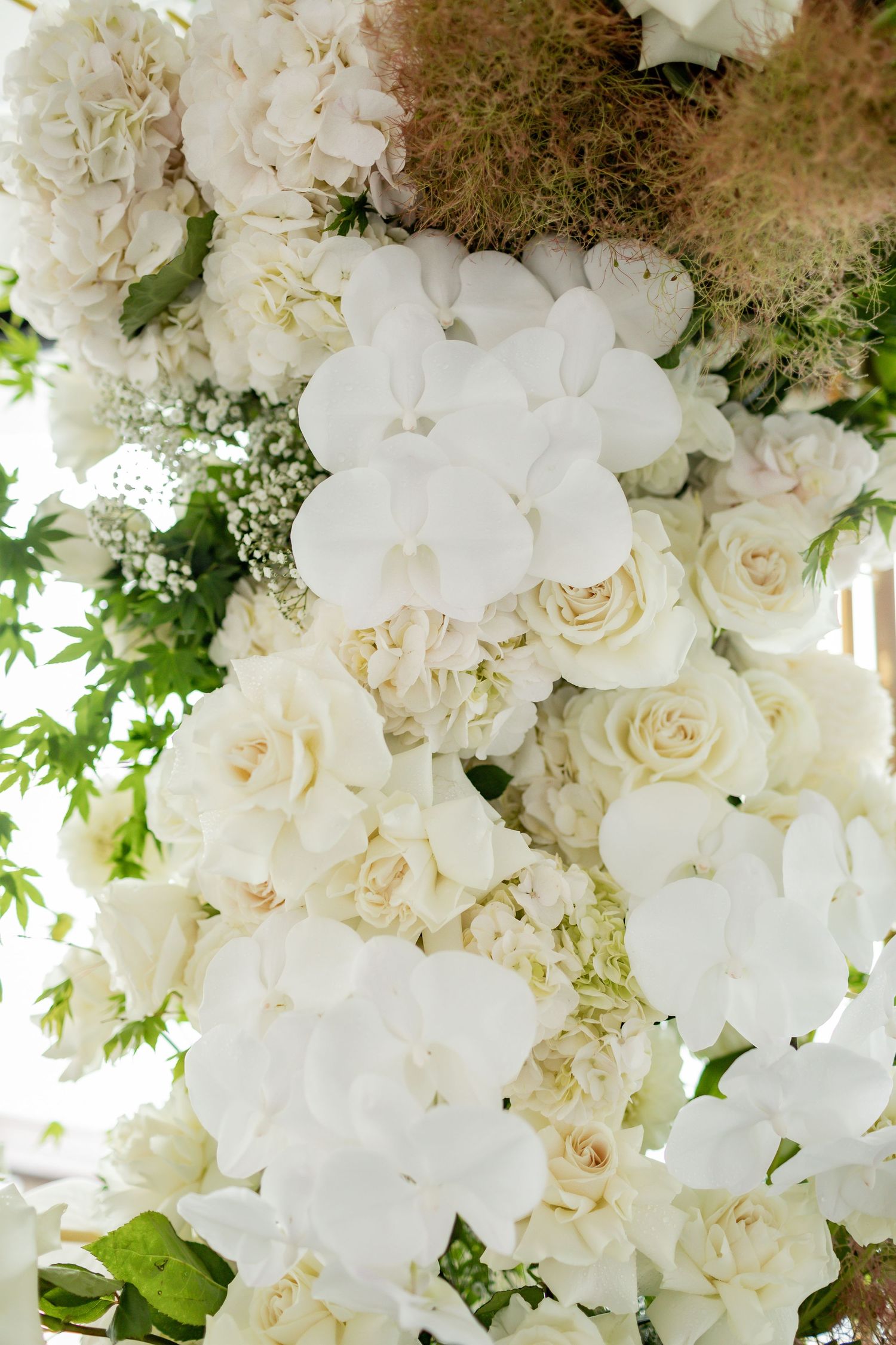Lush white floral arrangement featuring roses, hydrangeas and delicate greenery.