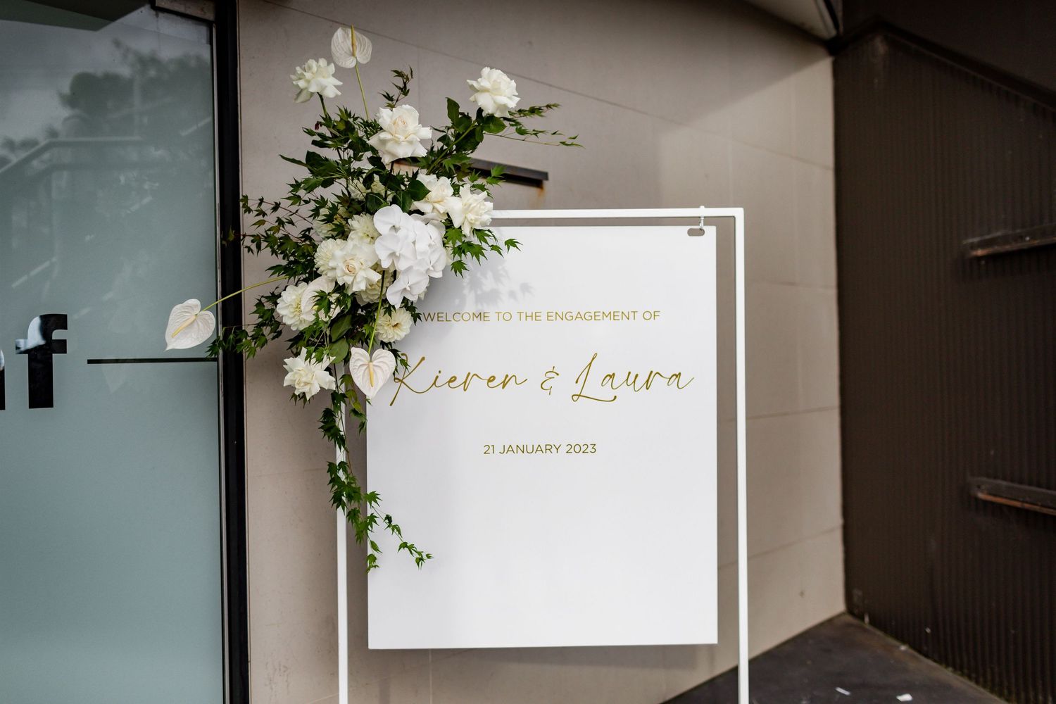 Elegant white wedding welcome sign decorated with fresh flowers and greenery.