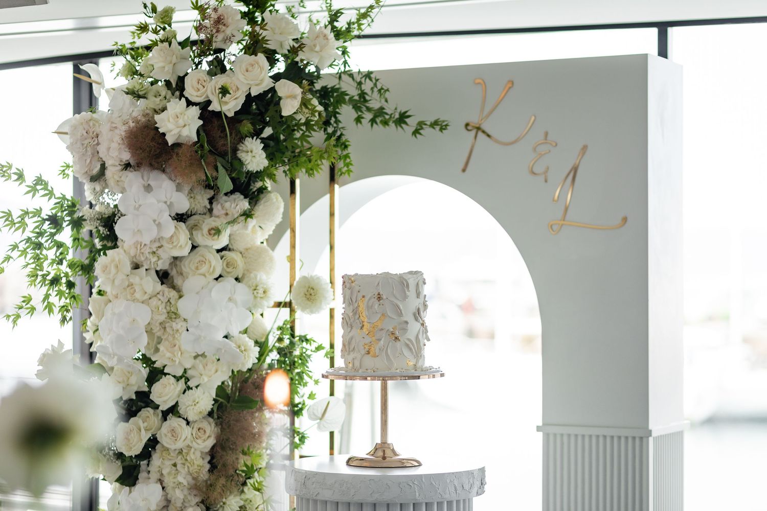 Luxurious white floral arch installation with wedding cake display.