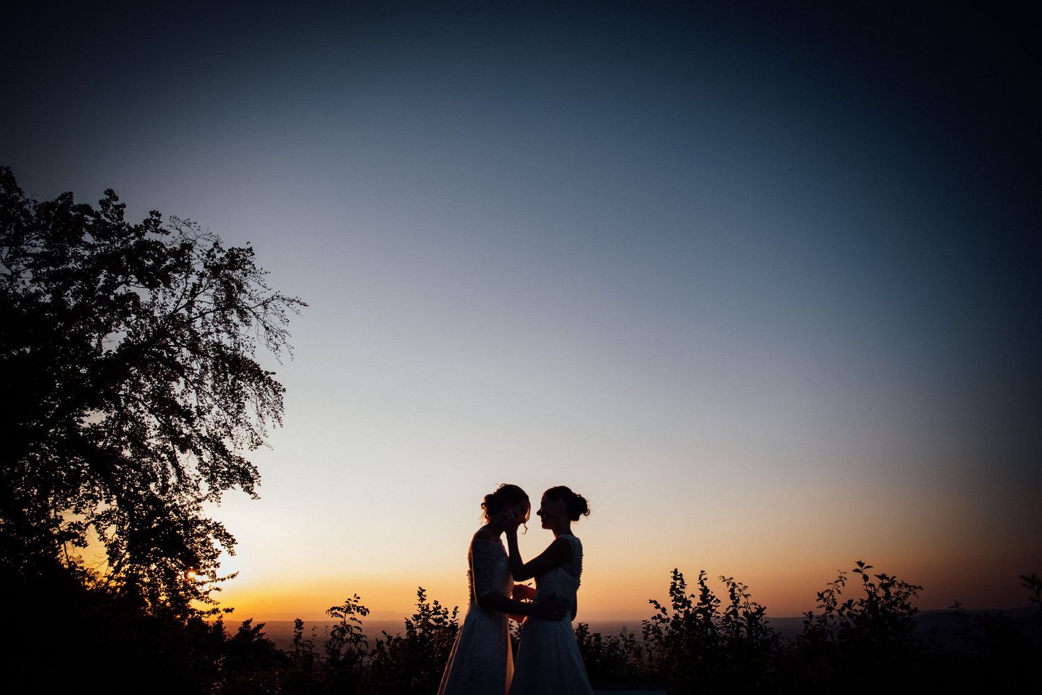 Silhouettes of a couple against a dramatic sunset sky.