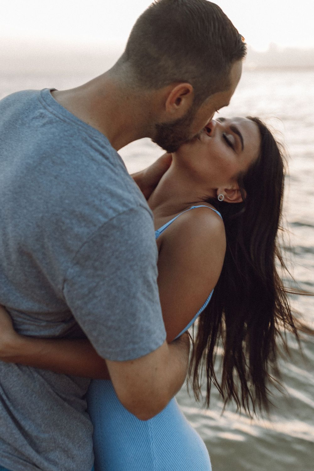 Beach engagement photo couple by the rocks and the ocean at sunset
