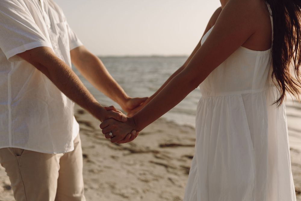 Beach engagement photo couple by the rocks and the ocean at sunset florida
