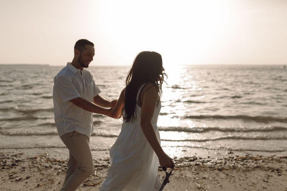 Beach engagement photo couple by the rocks and the ocean at sunset