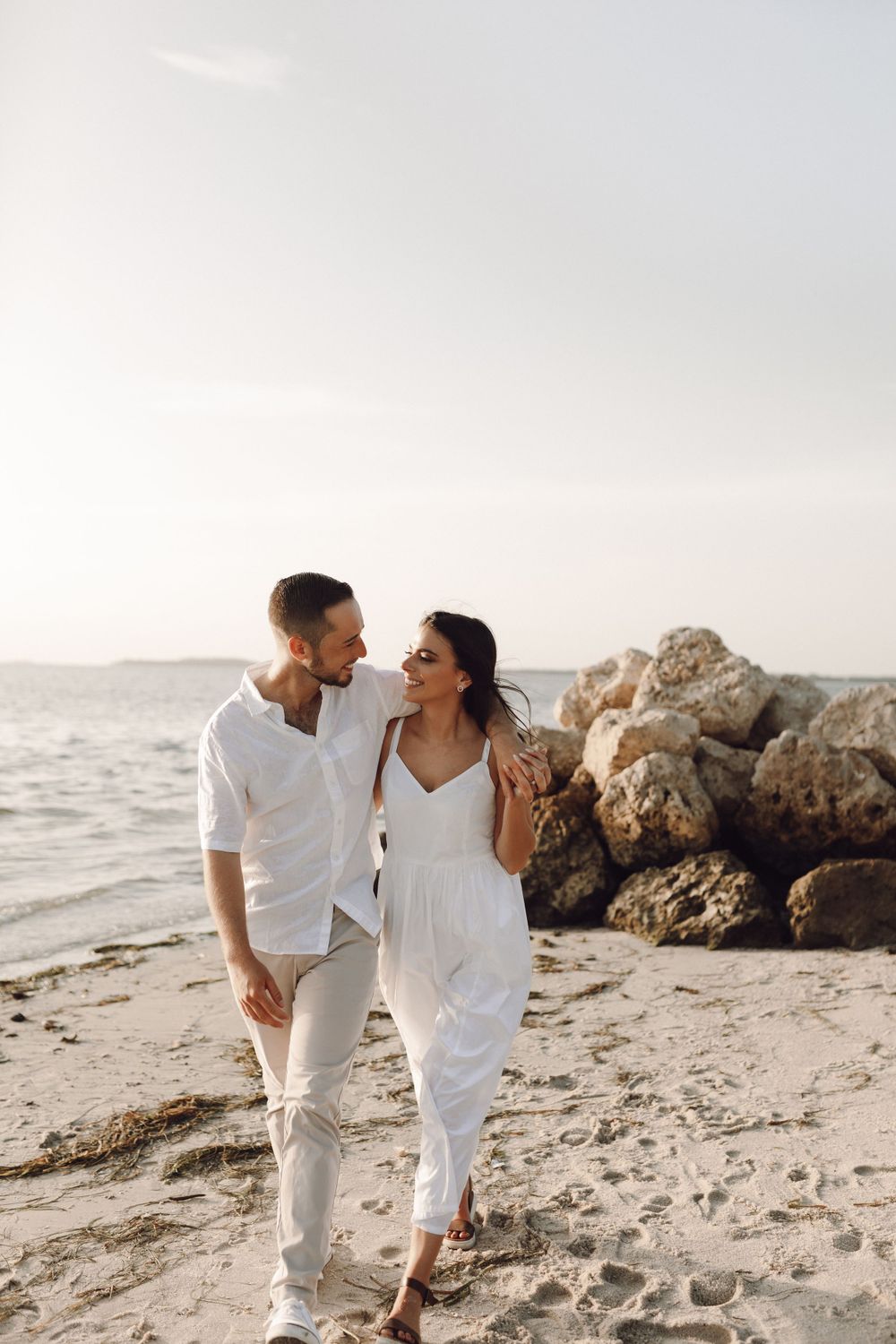 Beach engagement photo couple by the rocks and the ocean at sunset