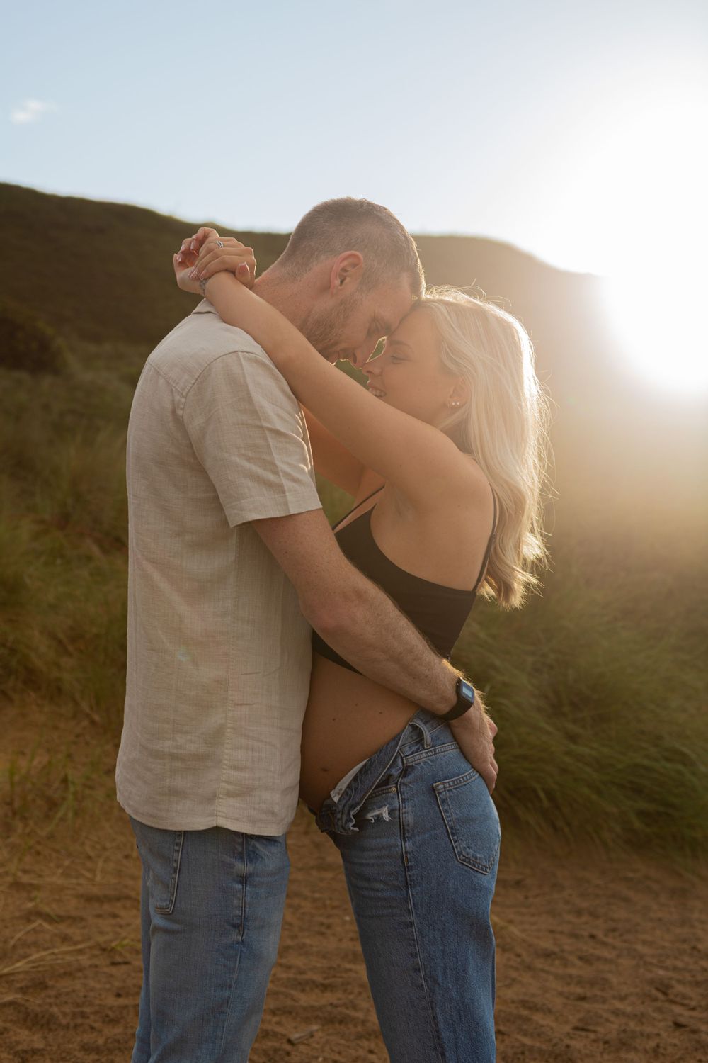 glowy sunset maternity session on the beach of couple sharing an intimate moment while bonding with bump