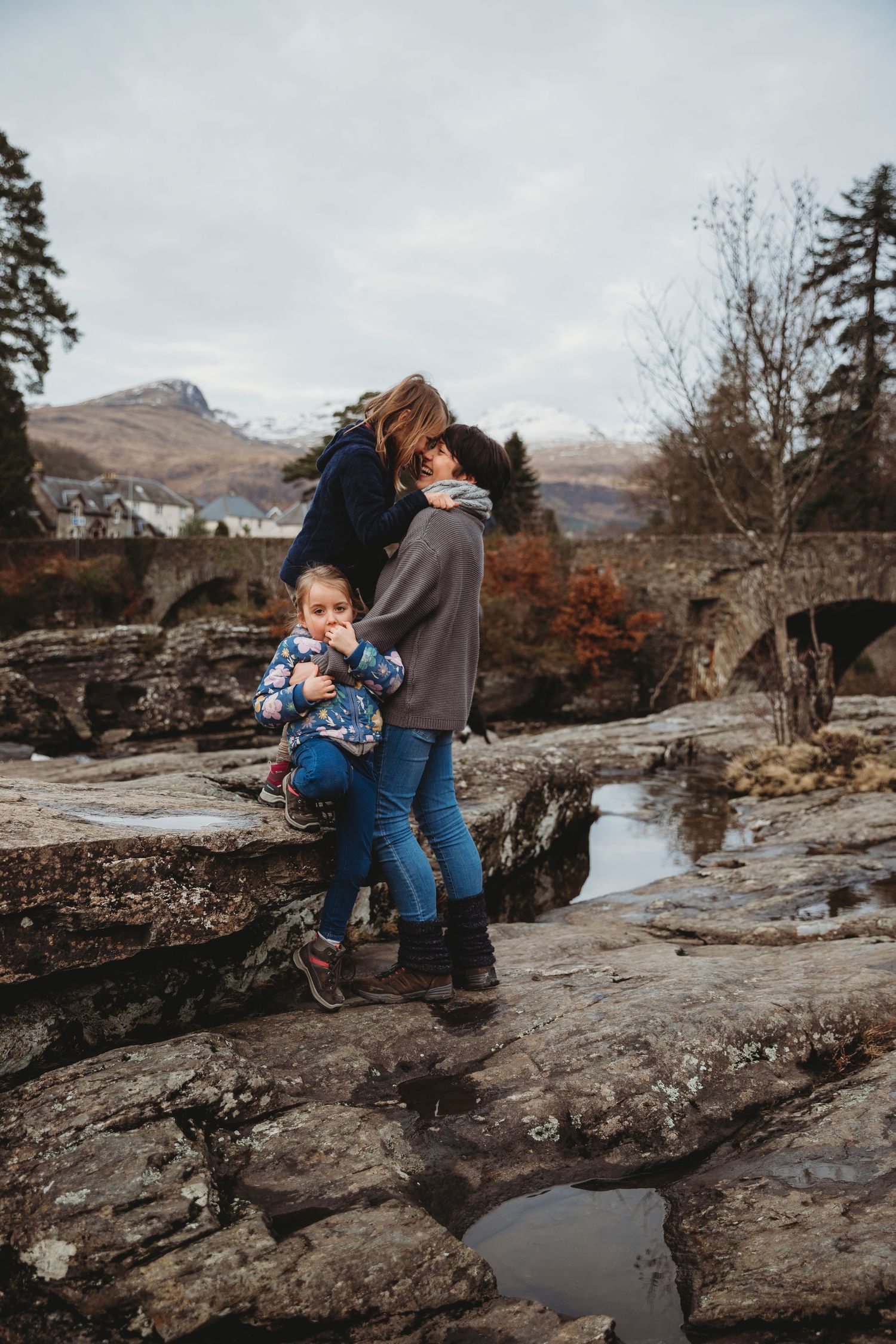 People exploring rocky terrain with mountains and autumn foliage in the background.