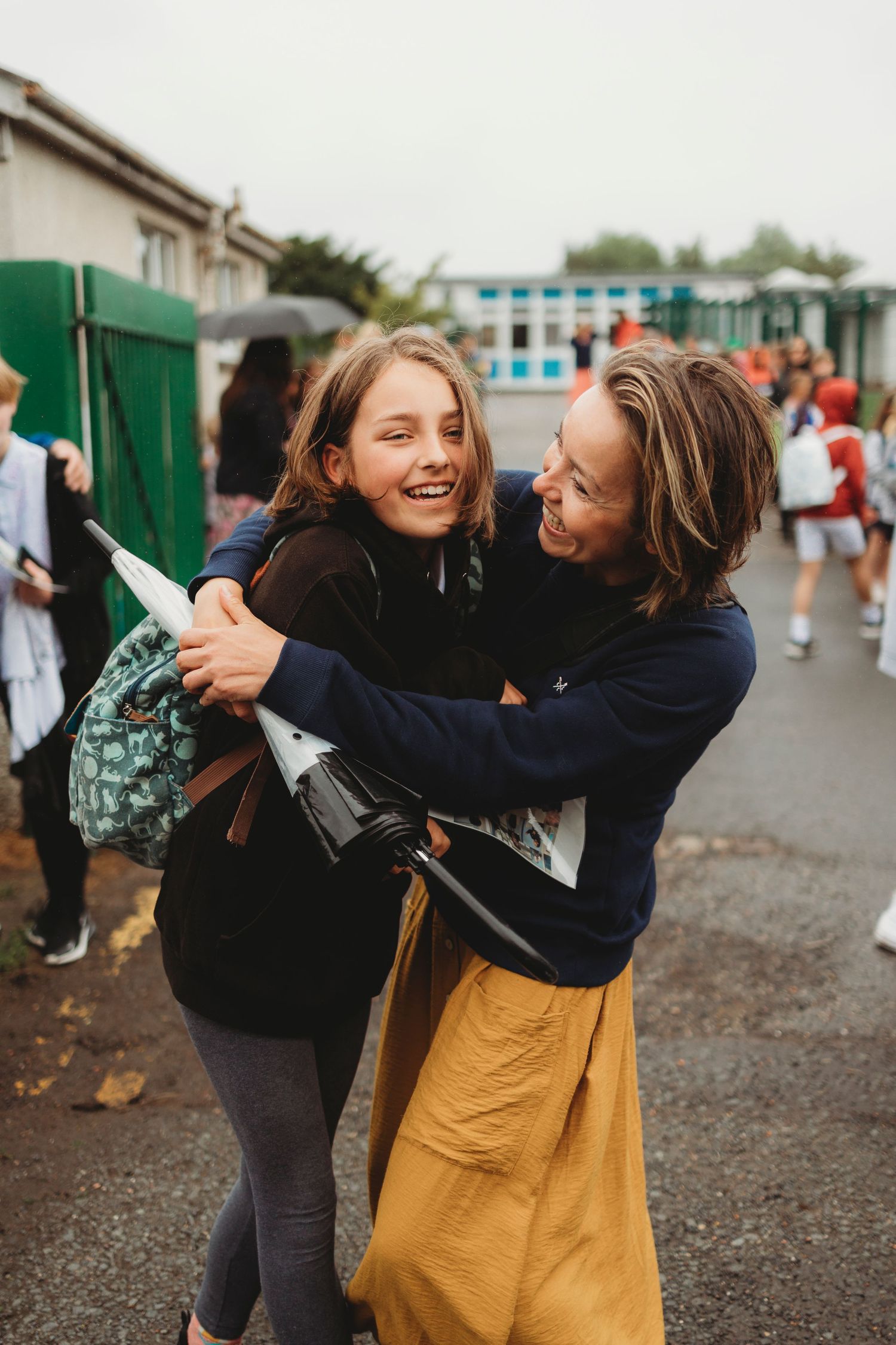 Two students share a joyful moment in a school courtyard.
