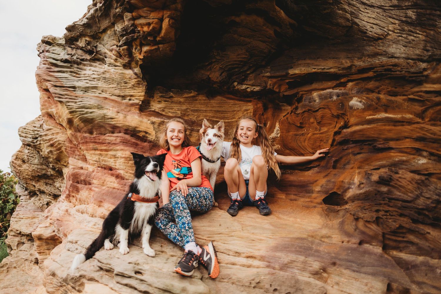 A group poses with their husky dog in a sandstone cave formation.
