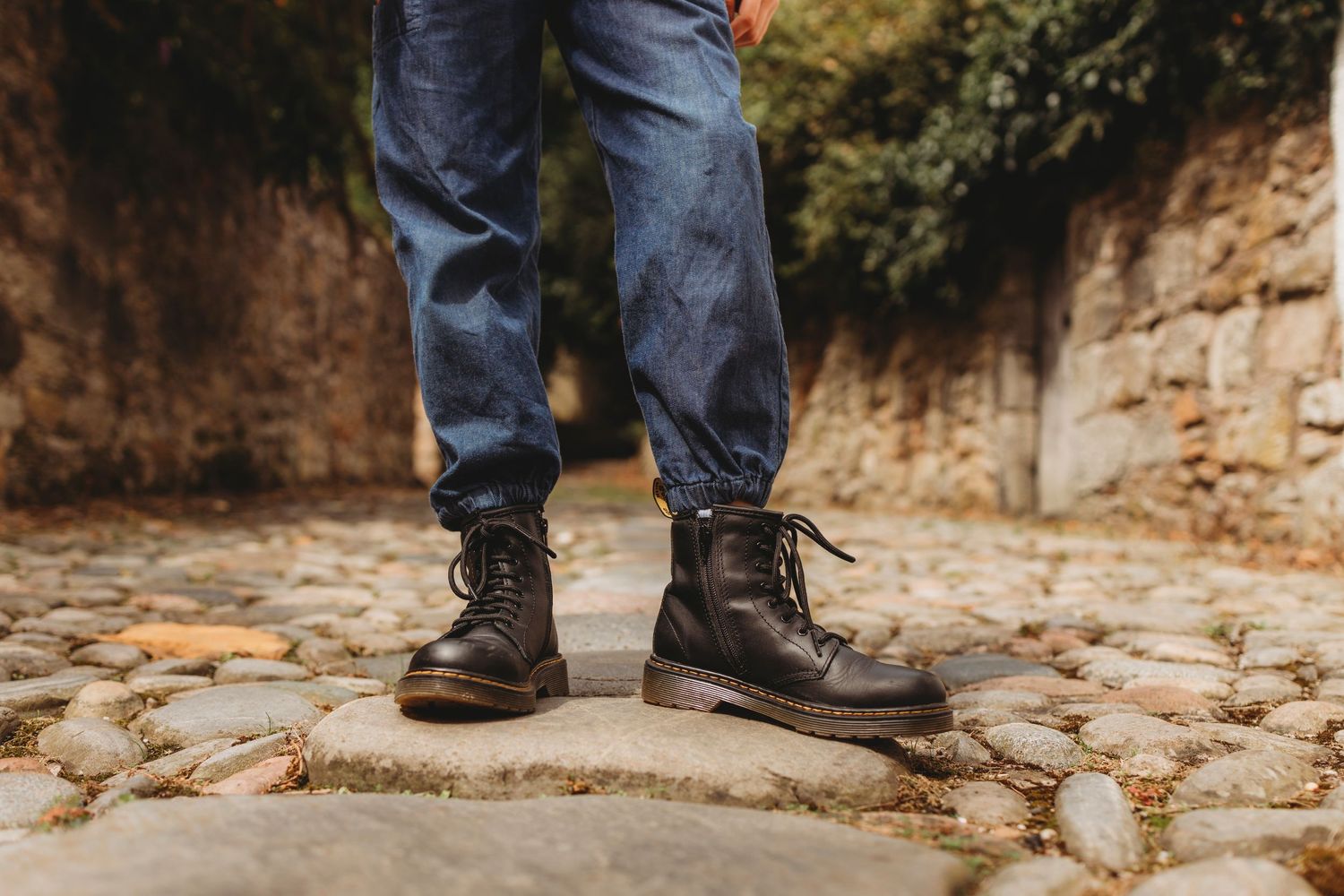 Close-up of brown leather boots on cobblestone ground.