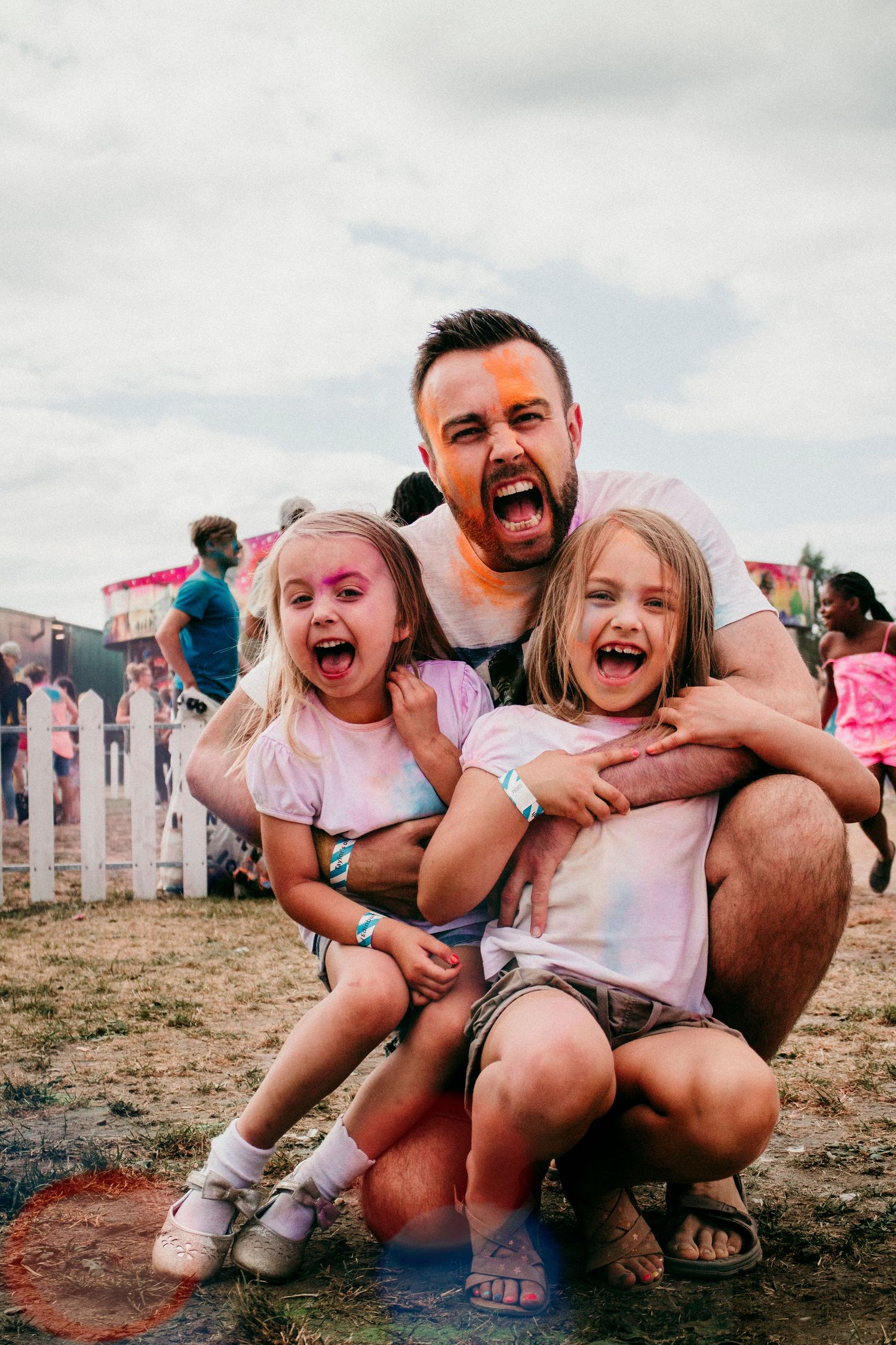 Joyful family moment captured outdoors against a white picket fence with matching expressions.