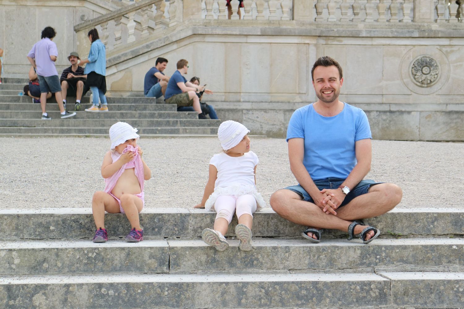 People relaxing on wide stone steps of a historic building on a sunny day.