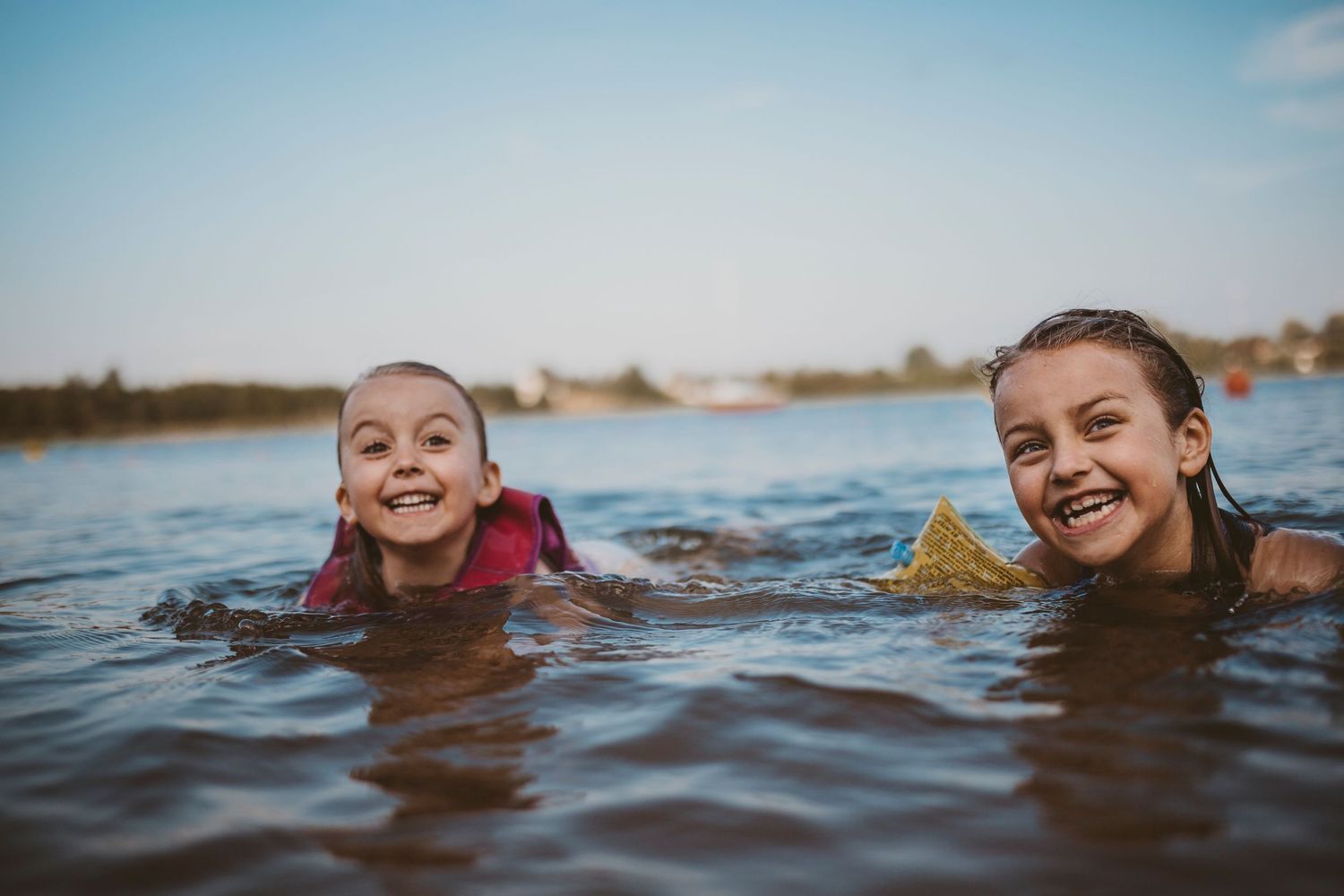 Two swimmers enjoying a refreshing dip in a lake on a sunny summer day.