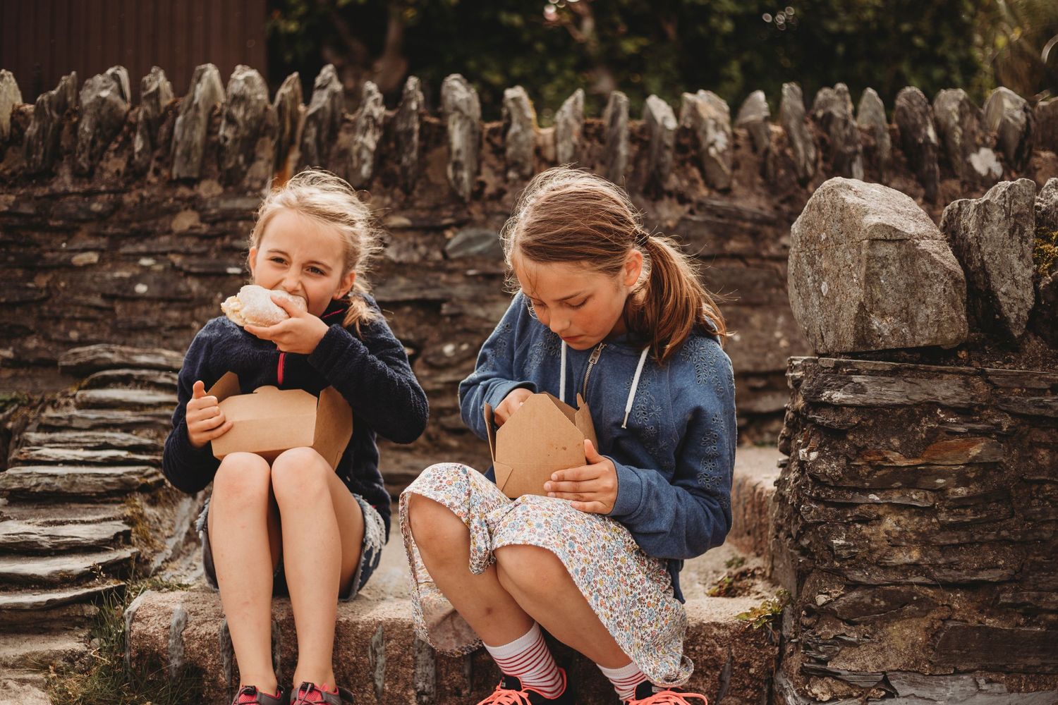 Children sitting on stone steps with pets in their laps.
