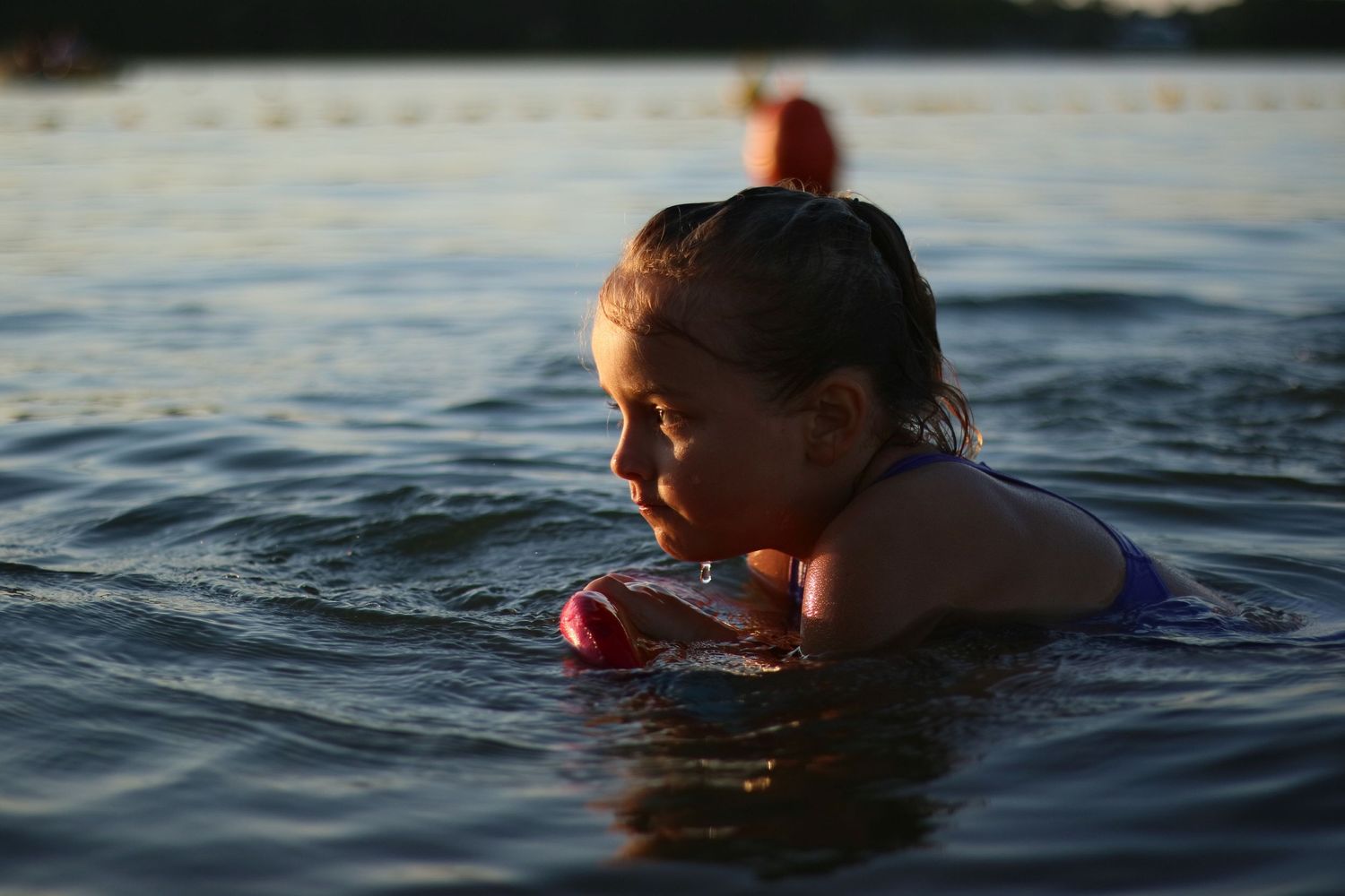A swimmer floats in calm waters during golden hour lighting.