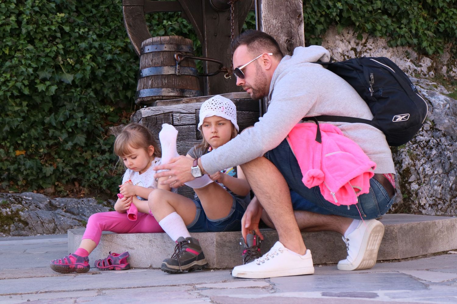 A family moment on stone steps surrounded by barrels and greenery.