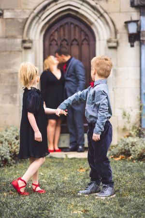 A mom and dad steal a kiss while their kids look away