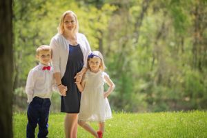 In a clearing, bathed in sunlight, a mother holds her children's hands and looks like a magazine cover