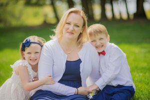 A stunning mother and her children sit in a field with golden light highlighting them