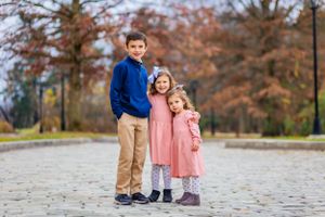 siblings embrace as their parents adoringly look at them from afar