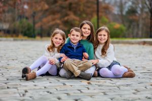 Siblings cuddle while their parents admire them from afar