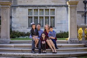 a family huddles close and smiles while sitting on stone steps