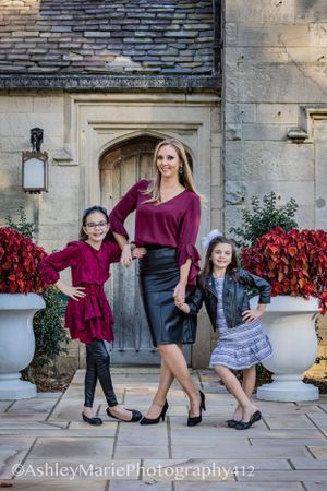 a tall blonde woman holds hands with two little girls