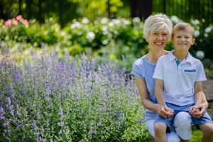 A grandmother and grandson sit adoringly by a field of flowers