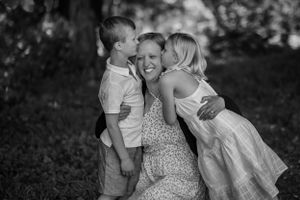 A mother is embraced by her children. She can't help but laugh