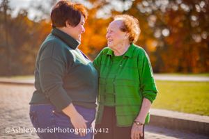 An elderly woman embraces her daughter while splashes of autumn leaves provide a breathtaking background