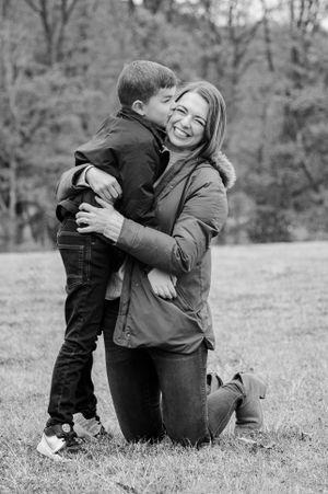 a mother kneels with her son and he gives her a big kiss on the cheek