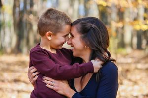 a mother and her son smile at each other and push their foreheads together