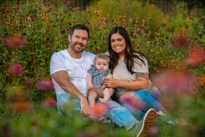 A family sits in a garden amongst colorful flowers