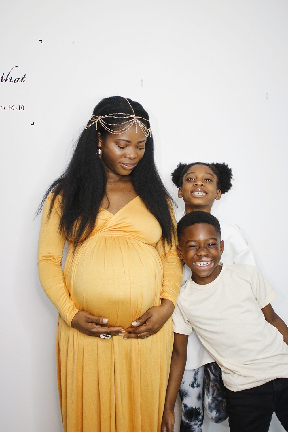 Heartwarming family photoshoot featuring a yellow dress and white t-shirt against a plain background.
