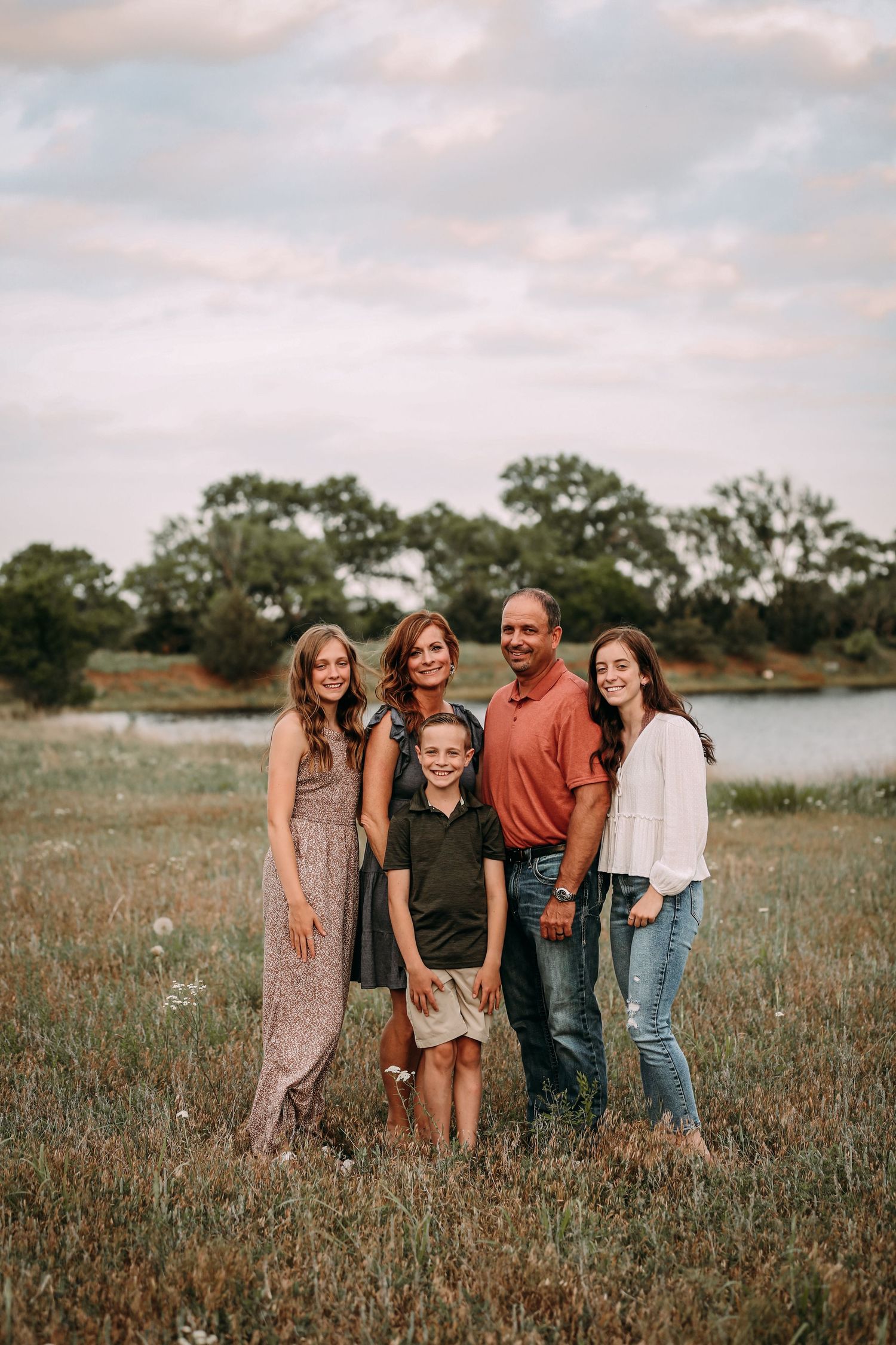 family of 5 smiling by water