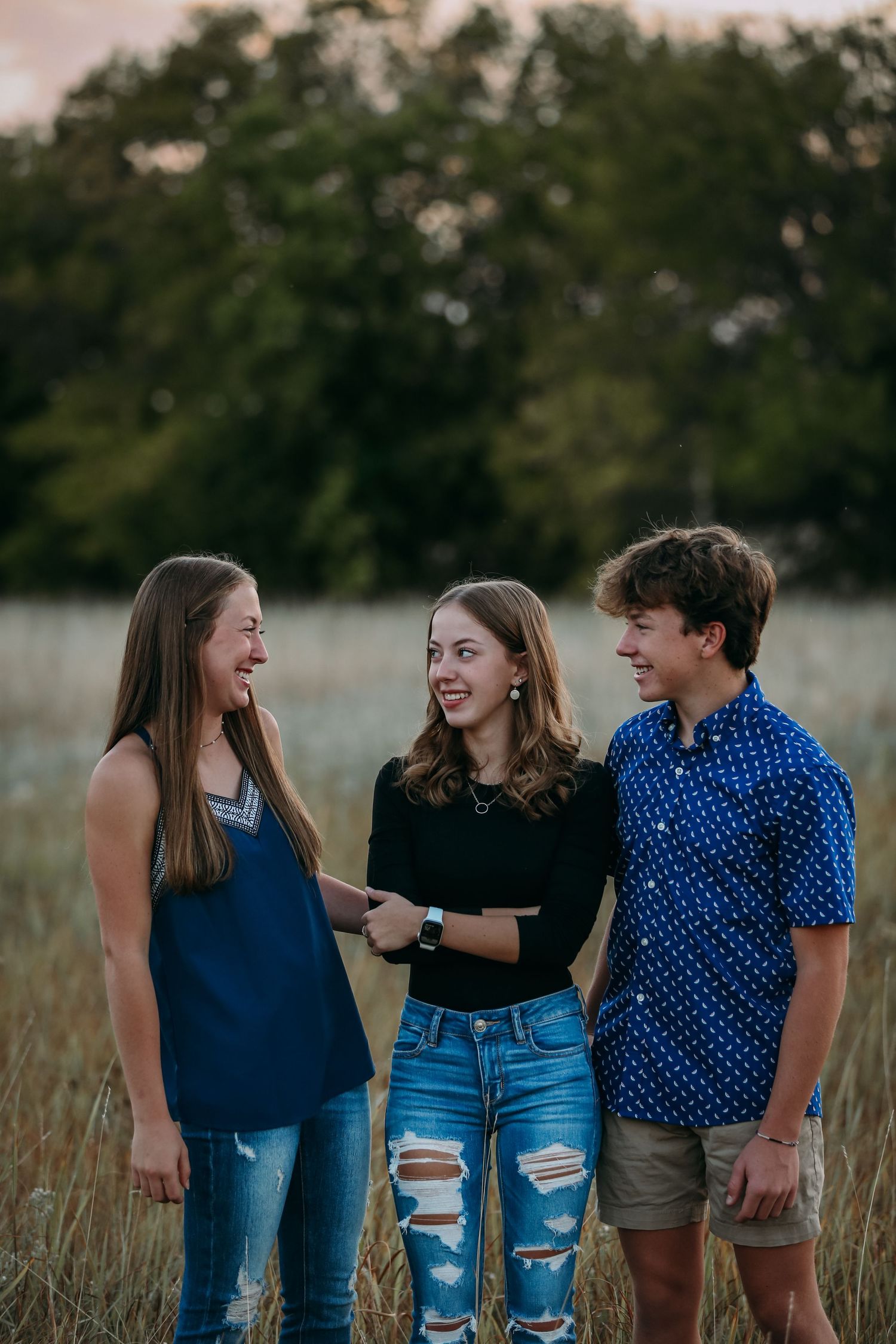 three siblings joking in a field